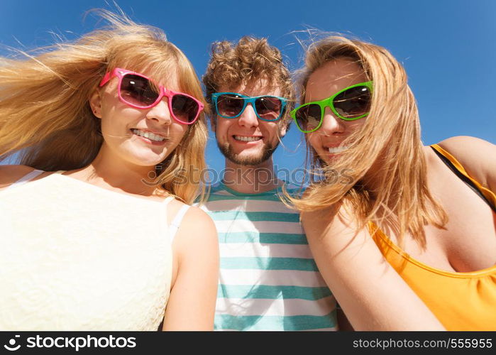 Friendship happiness summer holidays concept. Group of friends boy two girls in colorful sunglasses having fun outdoor against sky, joy playful mood.. Group friends boy two girls having fun outdoor