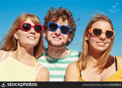 Friendship happiness summer holidays concept. Group of friends boy two girls in colorful sunglasses having fun outdoor against sky, joy playful mood.. Group friends boy two girls having fun outdoor