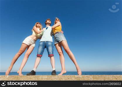 Friendship happiness summer holidays concept. Group of friends in full length boy two girls having fun outdoor. Wide angle view against sky. Group friends boy two girls having fun outdoor
