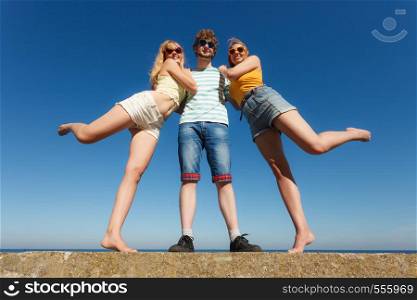 Friendship happiness summer holidays concept. Group of friends in full length boy two girls having fun outdoor. Wide angle view against sky. Group friends boy two girls having fun outdoor