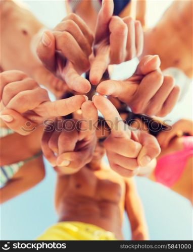 friendship, happiness, summer vacation, holidays and people concept - close up of smiling friends wearing swimwear standing in circle over blue sky