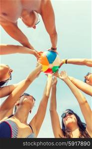 friendship, happiness, summer vacation, holidays and people concept - group of smiling friends wearing swimwear standing in circle with beach ball over blue sky