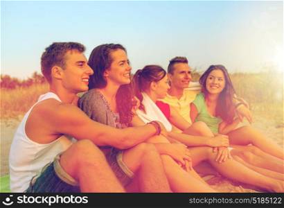 friendship, happiness, summer vacation, holidays and people concept - group of smiling friends sitting beach. smiling friends in sunglasses on summer beach