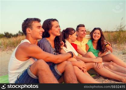 friendship, happiness, summer vacation, holidays and people concept - group of smiling friends sitting beach