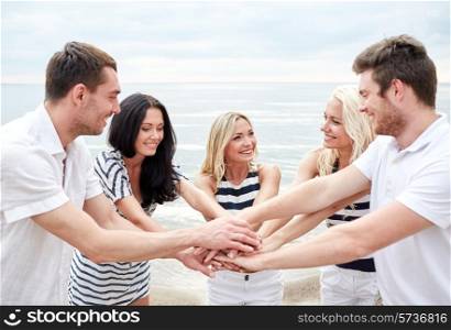 friendship, happiness, unity and people concept - smiling friends putting hands on top of each other