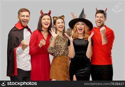 friendship, holiday and celebration concept - group of happy smiling friends in halloween costumes of vampire, devil, witch and leopard over grey background. happy friends in halloween costumes over grey