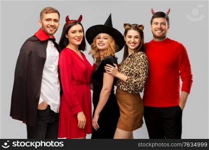 friendship, holiday and people concept - group of happy smiling friends in halloween costumes of vampire, devil, witch and cheetah over grey background. happy friends in halloween costumes over grey