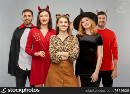 friendship, holiday and people concept - group of happy smiling friends in halloween costumes of vampire, devil, witch and leopard over grey background. happy friends in halloween costumes over grey