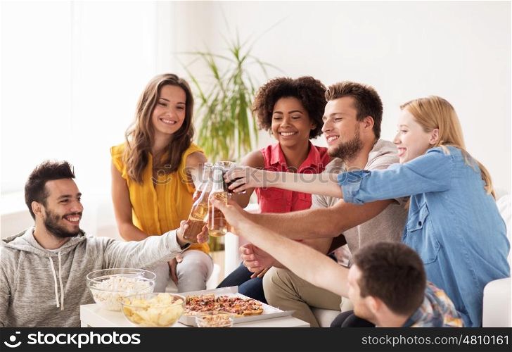 friendship, holidays, fast food and celebration concept - happy friends having party and clinking drinks at home