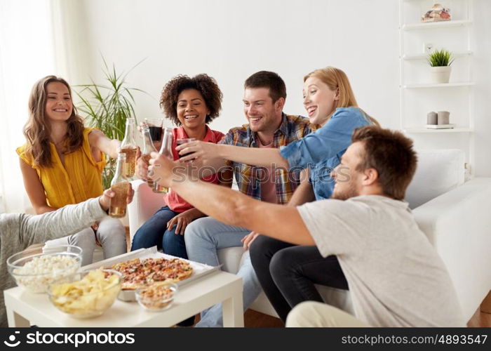 friendship, holidays, fast food and celebration concept - happy friends having party and clinking drinks at home
