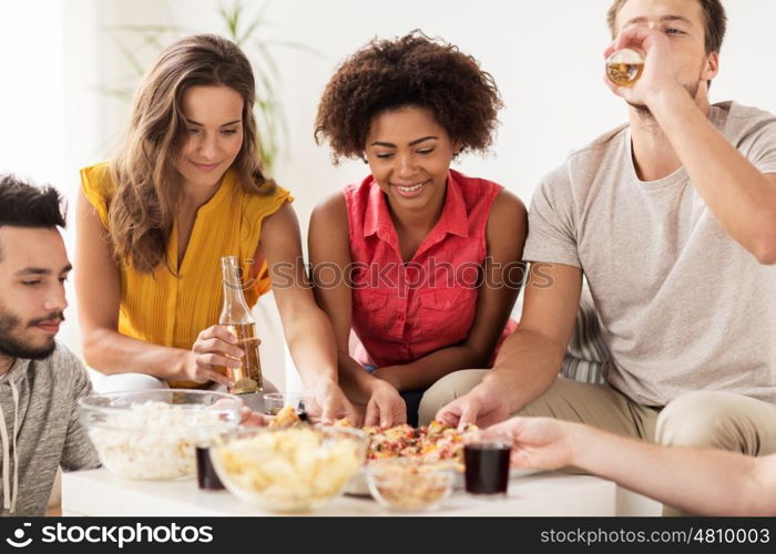 friendship, holidays, fast food and celebration concept - happy friends with drinks and snacks eating pizza at home