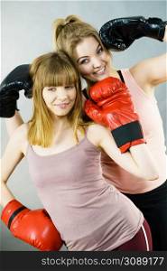 Friendship, human relations concept. Two happy women friends having fun smiling with joy wearing boxing gloves being fit and sporty.. Two women friends wearing boxing gloves