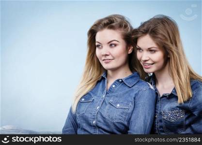 Friendship, human relations concept. Two happy women friends or sisters wearing jeans shirts having fun conversation.. Two happy women friends wearing jeans outfit