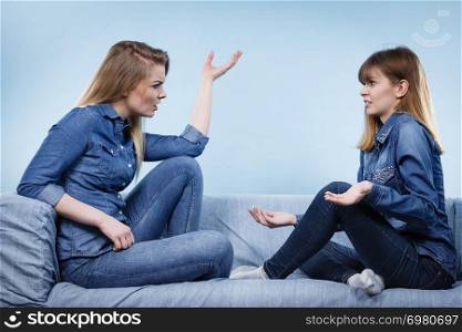 Friendship, human relations concept. Two happy women friends or sisters wearing jeans shirts having fun conversation.. Two happy women friends wearing jeans outfit talking