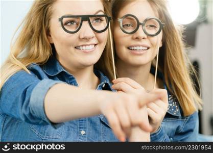Friendship, human relations concept. Two happy women friends or sisters wearing jeans shirts pointing somewhere.. Two happy women friends wearing jeans outfit poitning