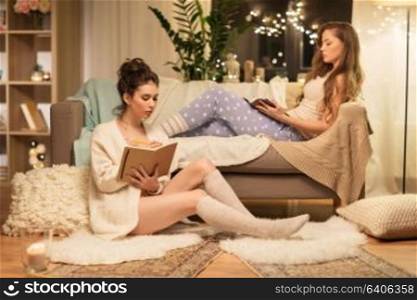 friendship, hygge and pajama party concept - happy female friends or teenage girls with book and diary at home. happy female friends with book and diary at home