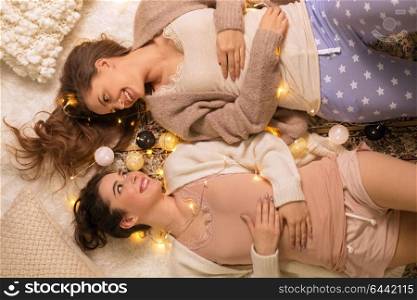 friendship, hygge and pajama party concept - happy female friends or teenage girls lying on floor at home. happy female friends in pajamas at home