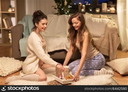 friendship, hygge and pajama party concept - happy female friends or teenage girls with cacao and waffles on tray at home. female friends with cacao and waffles at home