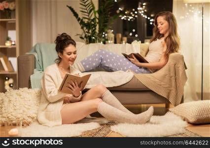 friendship, hygge and pajama party concept - happy female friends or teenage girls with book and diary at home. happy female friends with book and diary at home