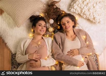 friendship, hygge and pajama party concept - happy female friends or teenage girls lying on floor at home. happy female friends in pajamas at home. happy female friends in pajamas at home