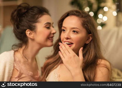 friendship, hygge and pajama party concept - happy female friends or teenage girls gossiping at home. happy female friends gossiping at home