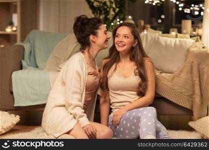 friendship, hygge and pajama party concept - happy female friends or teenage girls gossiping at home. happy female friends gossiping at home