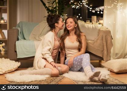 friendship, hygge and pajama party concept - happy female friends or teenage girls gossiping at home. happy female friends gossiping at home