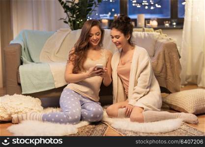 friendship, hygge and technology concept - happy female friends or teenage girls with smartphone at home. happy female friends with smartphone at home