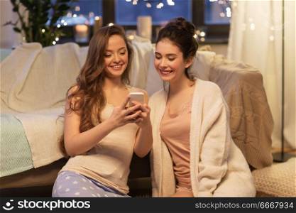 friendship, hygge and technology concept - happy female friends or teenage girls with smartphone at home. happy female friends with smartphone at home. happy female friends with smartphone at home