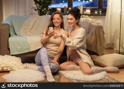 friendship, hygge and technology concept - happy female friends or teenage girls with smartphone at home. happy female friends with smartphone at home. happy female friends with smartphone at home