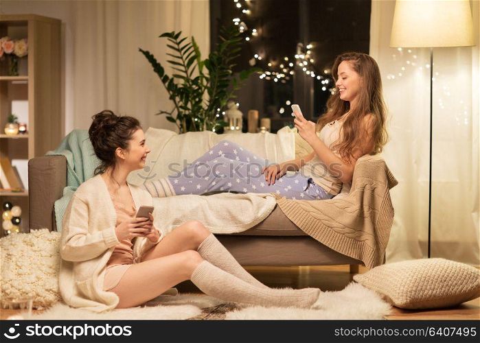 friendship, hygge and technology concept - happy female friends or teenage girls with smartphones at home. happy female friends with smartphones at home