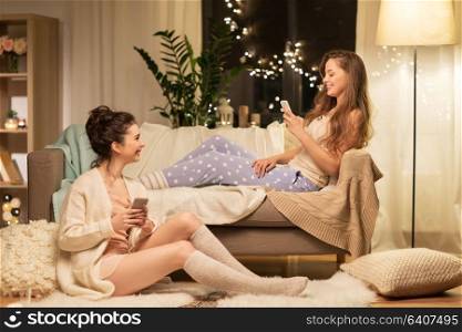 friendship, hygge and technology concept - happy female friends or teenage girls with smartphones at home. happy female friends with smartphones at home