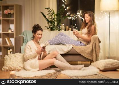 friendship, hygge and technology concept - happy female friends or teenage girls with smartphones at home. happy female friends with smartphones at home. happy female friends with smartphones at home