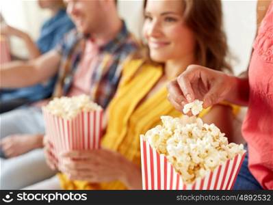 friendship, junk food and people concept - close up of happy smiling friends eating popcorn at home