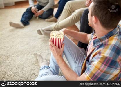 friendship, junk food and people concept - close up of man with friends eating popcorn at home. close up of man with friends and popcorn at home