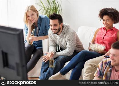 friendship, junk food, people and entertainment concept - happy friends with popcorn and beer watching tv at home