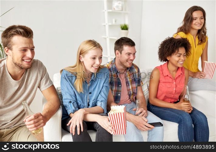 friendship, junk food, people and entertainment concept - happy friends with popcorn and beer watching tv at home