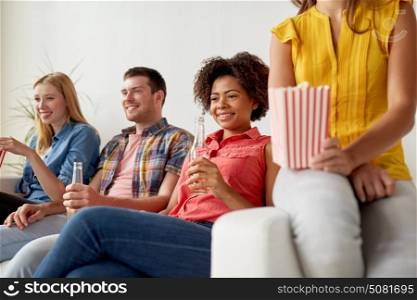 friendship, junk food, people and entertainment concept - happy friends with popcorn and beer watching tv at home. happy friends with popcorn watching tv at home