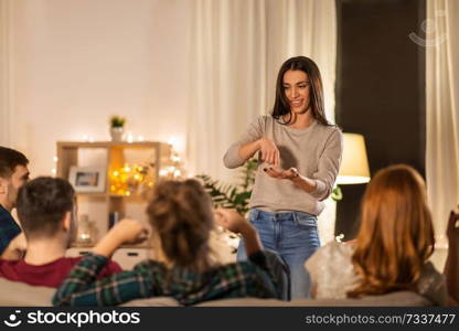 friendship, leisure and entertainment concept - happy friends playing charades game at home in evening. happy friends playing charades at home in evening