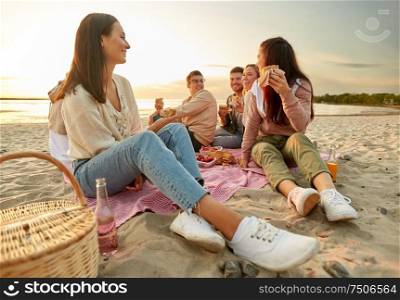 friendship, leisure and fast food concept - group of happy friends eating sandwiches or burgers at picnic on beach in summer. happy friends eating sandwiches at picnic on beach