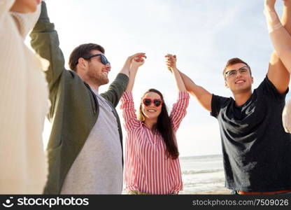 friendship, leisure and people concept - group of happy friends holding hands on beach in summer. happy friends holding hands on summer beach