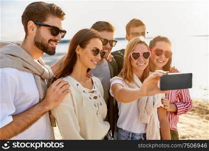 friendship, leisure and people concept - group of happy friends taking selfie by smartphone on beach in summer. happy friends taking selfie on summer beach