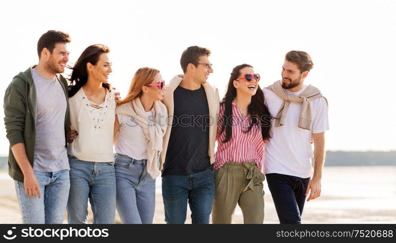 friendship, leisure and people concept - group of happy friends walking along beach in summer. happy friends walking along summer beach