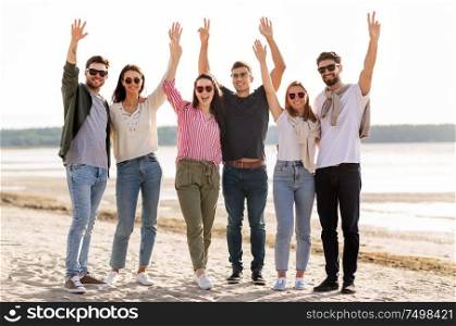 friendship, leisure and people concept - group of happy friends waving hands on beach in summer. happy friends waving hands on beach in summer