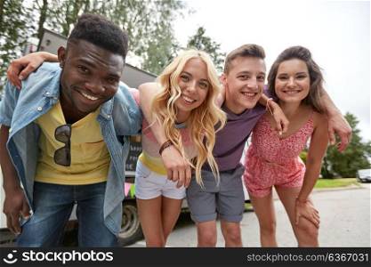 friendship, leisure and people concept - group of happy smiling friends hugging outdoors at food truck. group of happy friends hugging at food truck