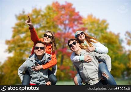 friendship, leisure and people concept - group of happy teenage friends in sunglasses having fun over autumn park background. happy friends in shades having fun in autumn park