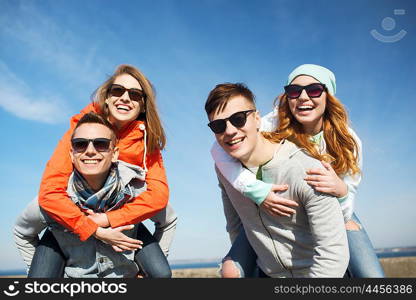 friendship, leisure and people concept - group of happy teenage friends in sunglasses having fun outdoors