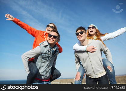 friendship, leisure and people concept - group of happy teenage friends in sunglasses having fun outdoors