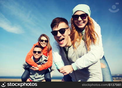 friendship, leisure and people concept - group of happy teenage friends in sunglasses having fun outdoors