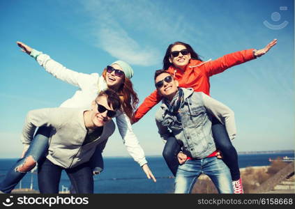 friendship, leisure and people concept - group of happy teenage friends in sunglasses having fun outdoors